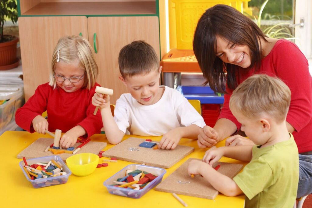 A teacher helping preschoolers with a building activity